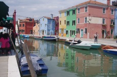 Brightly colored buildings reflect in a canal in Burano